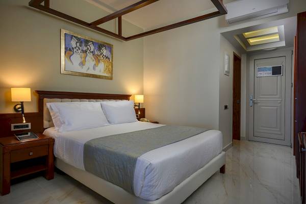 Hotelzimmer im Vantaris Palace mit einem Bett, Nachttisch und einem Kunstwerk an der Wand.
