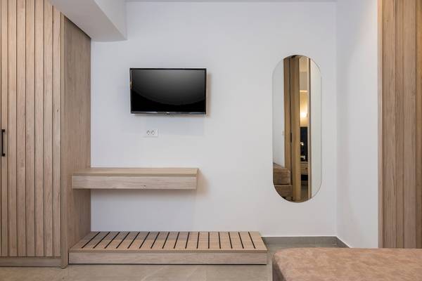 Innenansicht eines Zimmers im Vantaris Palace Hotel mit einer Wand, einem Fernseher und einem Spiegel.