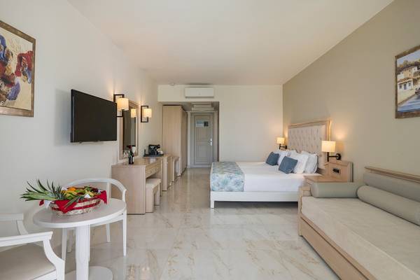 Innenansicht der Suite im Vantaris Palace Hotel mit Bett, Schreibtisch und Früchtekorb.