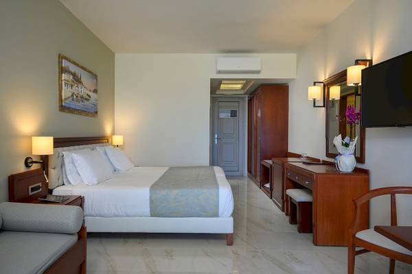 Hotelzimmer im Vantaris Palace mit Bett, Nachttischen, Fernseher und Schreibtisch.
