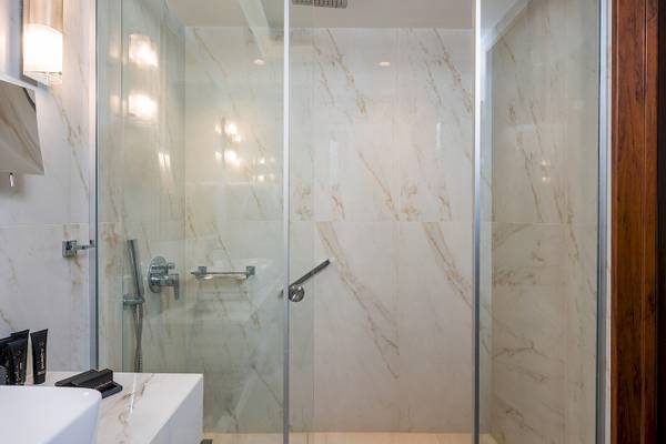 Vantaris Palace Badezimmer mit einer großen Glasdusche und Marmorwänden.
