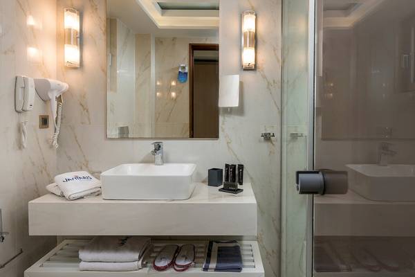 Badezimmer im Vantaris Palace Hotel mit Waschbecken, Handtüchern und Toilettenartikeln.