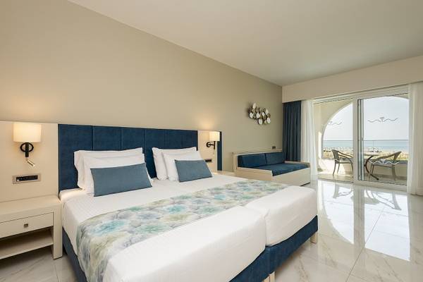 Hotelzimmer im Vantaris Palace mit Blick auf das Meer und eine Terrasse mit Stühlen.