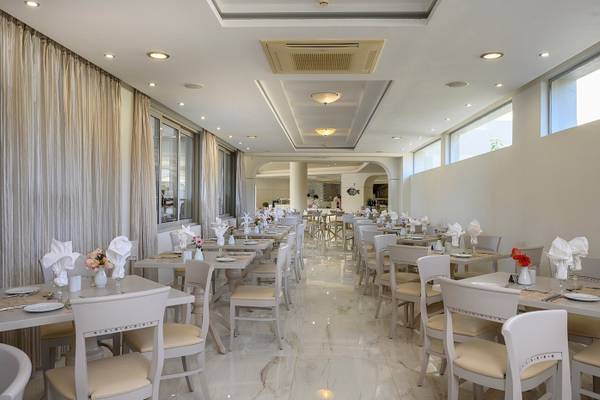 Innenansicht des Restaurants im Vantaris Palace mit weißen Tischen und Stühlen, Marmorboden und weißen Vorhängen.