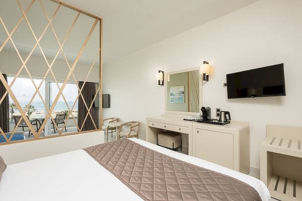 Hotelzimmer mit Meerblick im Vantaris Palace mit einem großen Bett, einem Schreibtisch und einem Fernseher an der Wand.