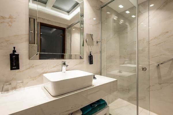 Das Badezimmer im Vantaris Palace mit weißem Waschbecken und Spiegeln.