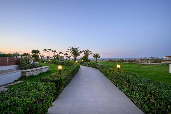 Gartenweg im Vantaris Palace Hotel bei Sonnenuntergang mit Palmen und Laternen