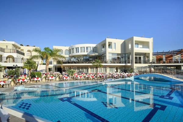 Außenbereich des Vantaris Palace Hotels mit Swimmingpool und mehreren Tischen und Stühlen.