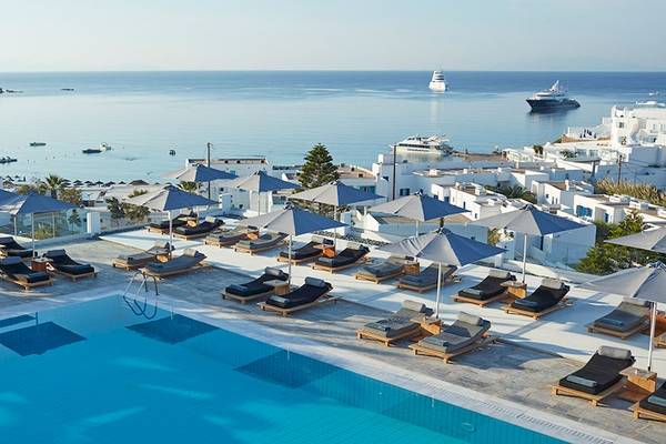 Poolbereich des Myconian Ambassador Relais & Chateaux Hotels mit Blick auf das Meer und Schiffe.