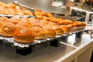 Frühstücksbuffet im Hotel Colonial Barcelona mit verschiedenen Brötchen, Croissants und Muffins.