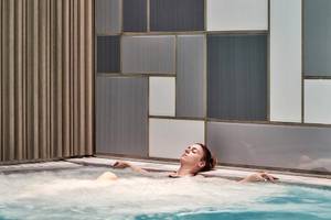 Eine Frau genießt ein entspannendes Bad im Schwimmbad des Myconian Ambassador Relais & Chateaux.