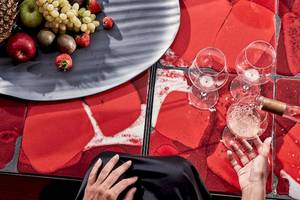 Frühstück im Bett im Myconian Ambassador Relais & Chateaux mit Früchten und Sekt auf rotem Tisch