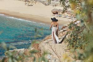 Gast des Myconian Ambassador Relais & Chateaux auf einer Felskante am Strand