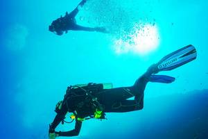 Scuba-Taucher schwimmen im Meer und erkunden die Unterwasserwelt.
