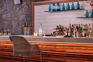 Bar-Theke im Myconian Ambassador Relais & Chateaux Hotel mit vielen Flaschen und Gläsern.