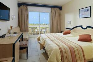 Zimmer im Djerba Holiday Beach Hotel mit zwei Betten, Balkon, Fernseher und Schreibtisch.