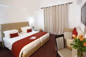 Doppelzimmer im Djerba Holiday Beach Hotel mit Doppelbett, Sofa, Tisch, Stuhl und Fernseher.