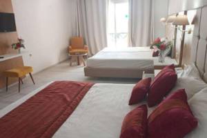 Zwei Betten in einem Hotelzimmer im Djerba Holiday Beach Hotel mit roten Kissen und weißem Laken.