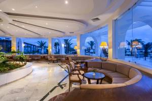 Lobby des Djerba Holiday Beach Hotels mit Sitzbereichen, Tischen und großen Glaswänden.