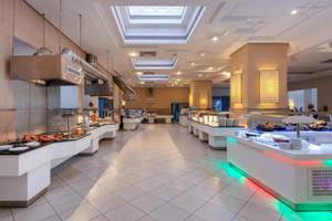 Foto von der Inneneinrichtung des Restaurants im Djerba Holiday Beach Hotel mit gepolsterten Stühlen und Buffets.