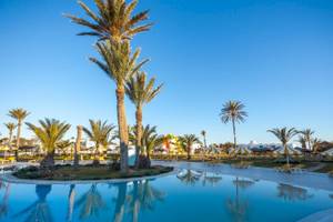 Außenpoolbereich des Djerba Holiday Beach Hotels mit Palmen, Sonnenliegen und gelben Sonnenschirmen.