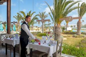 Ein Kellner serviert einen Tisch im Freien im Djerba Holiday Beach Hotel.