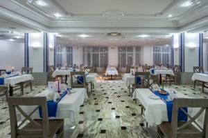 Innenansicht des Restaurants im Djerba Holiday Beach Hotel mit gedeckten Tischen und Stühlen.