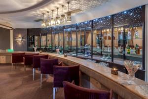 Innenansicht der Bar im Djerba Holiday Beach Hotel mit Stühlen und Theke.