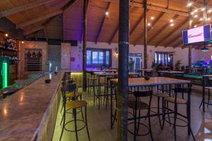 Innenbereich des Djerba Holiday Beach Hotels mit Bar, Tischen und Stühlen.