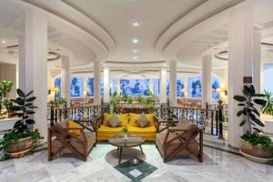 Lobby des Djerba Holiday Beach Hotels mit gelber Couch, Tischen und Pflanzen.