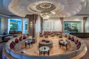 Lobby des Djerba Holiday Beach Hotels mit großen Sofas, Tischen und einer beeindruckenden Deckenleuchte.