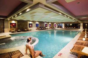 Eine Frau sitzt am Rand eines großen Innenpools im Crystal Deluxe Resort & Spa.