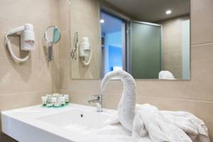 Badezimmer im Irene Palace Beach Resort mit Waschbecken, Handtüchern und Haartrocknern.