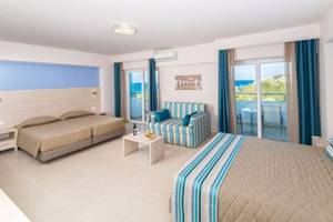 Zimmer im Irene Palace Beach Resort mit zwei Betten, einem Sofa und einem Balkon mit Meerblick.