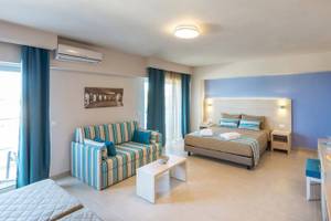 Innenansicht eines Zimmers im Irene Palace Beach Resort mit einem Bett, einem Sofa und einem Tisch.