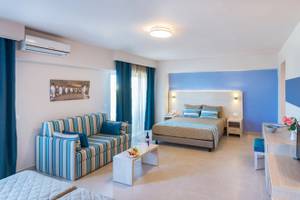 Inneneinrichtung eines Zimmers im Irene Palace Beach Resort mit einem Doppelbett, einer Couch, einem Tisch und einer Klimaanlage.