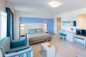 Modernes Zimmer im Irene Palace Beach Resort mit Bett, Tisch, Fernseher und Badezimmer