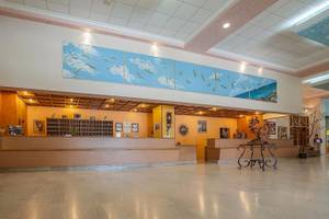 Empfangsbereich des Irene Palace Beach Resorts mit großen Wandgemälden und Möbeln.