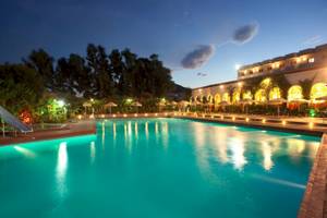 Pool des Irene Palace Beach Resorts bei Nacht mit leuchtenden Lichtern und einem Wasserrutsche
