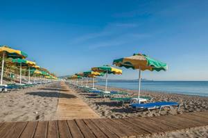 Reihe von Sonnenliegen und Sonnenschirmen am Strand des Irene Palace Beach Resorts