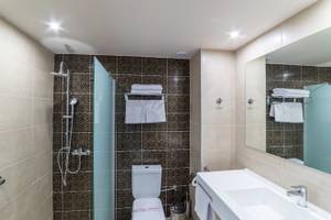 Badezimmer im Irene Palace Beach Resort mit Dusche, Toilette, Waschbecken und Spiegel.