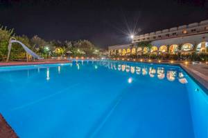 Nachtansicht des Swimmingpools im Irene Palace Beach Resort mit blauem Wasser und leuchtenden Lichtern.