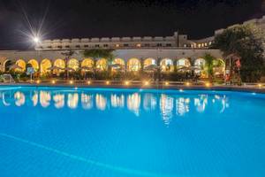 Nachtansicht des Irene Palace Beach Resorts mit großem Pool und beleuchteten Gebäuden