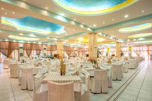 Ein großes geräumiges Restaurant im Irene Palace Beach Resort mit vielen gedeckten Tischen.