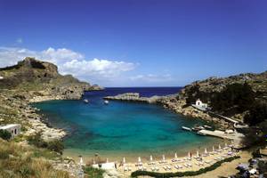 Landschaftsfoto des Irene Palace Beach Resorts mit türkisfarbenem Wasser und weißen Liegestühlen.