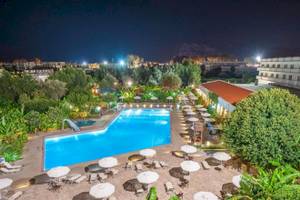 Nachtansicht des Irene Palace Beach Resorts mit Swimmingpool, Sonnenliegen und Schirmen.