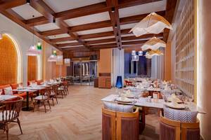 Innenbereich des Delphin Palace Restaurants mit orangefarbenen Wänden, Holztischen und Stühlen.