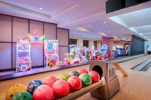 Bowlinghalle im Delphin Palace Hotel mit bunten Bowlingkugeln und Arcade-Spielautomaten.
