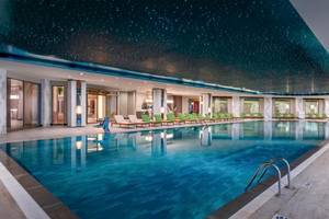 Poolbereich im Delphin Palace Hotel mit Sternenhimmeldecke und grünen Liegen