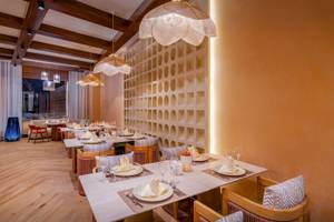 Innenansicht des Restaurants Delphin Palace mit gedeckten Tischen und hängenden Lampen.